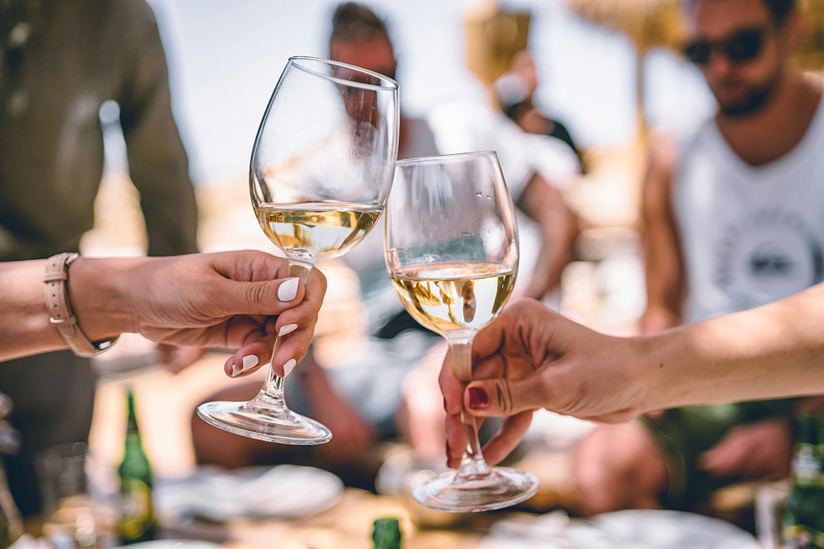 Enjoying a glass of white wine at the beach (image by Zan Lazarevic via unsplash)